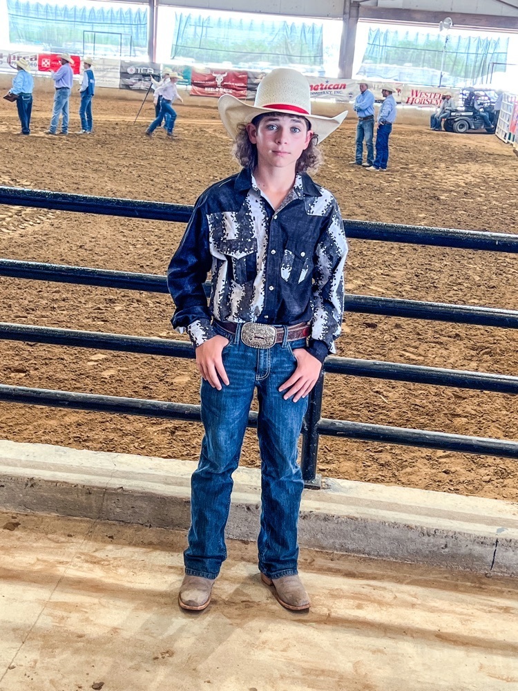 Jaxson McNutt in cowboy hat in front of rodeo ring