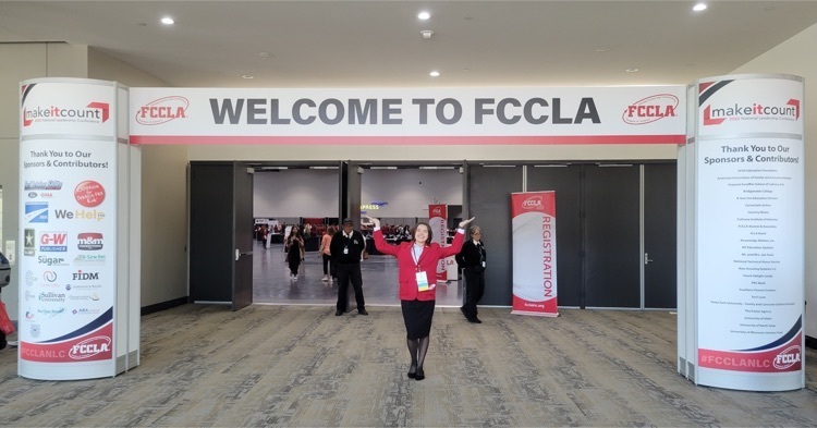 Emma DeRise with a sign reading “Welcome to FCCLA” above her