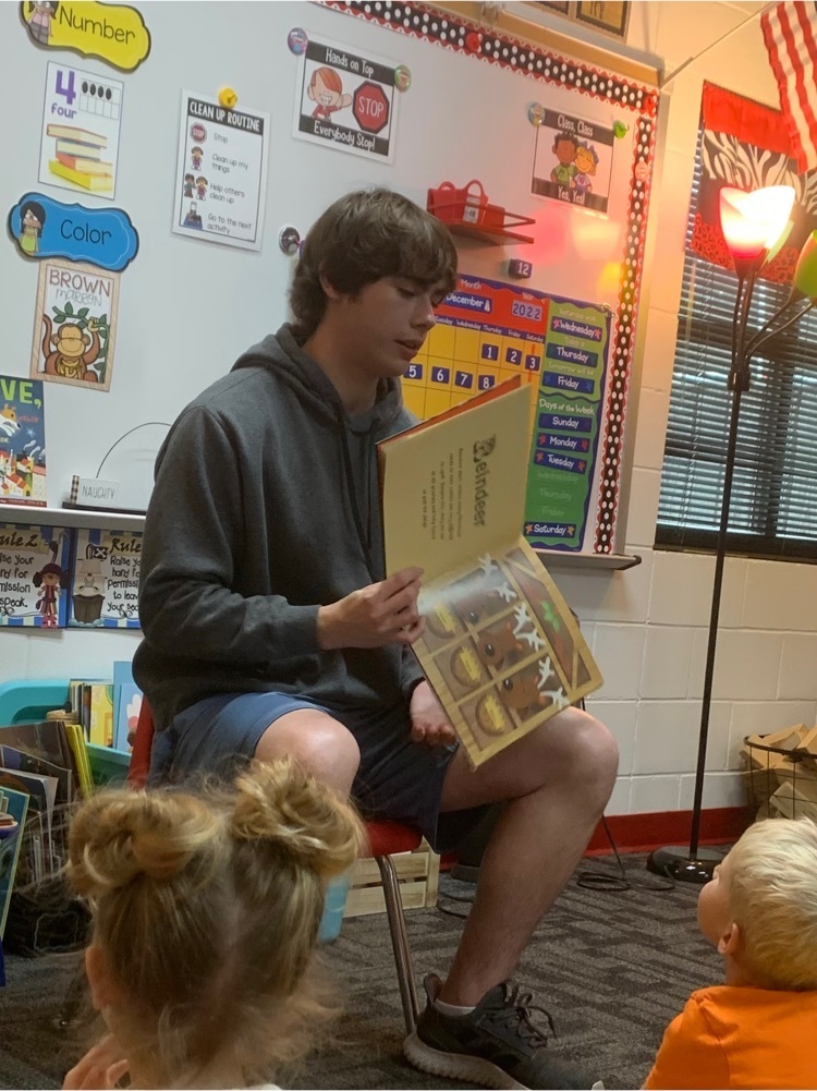 a student reading a book to the students 